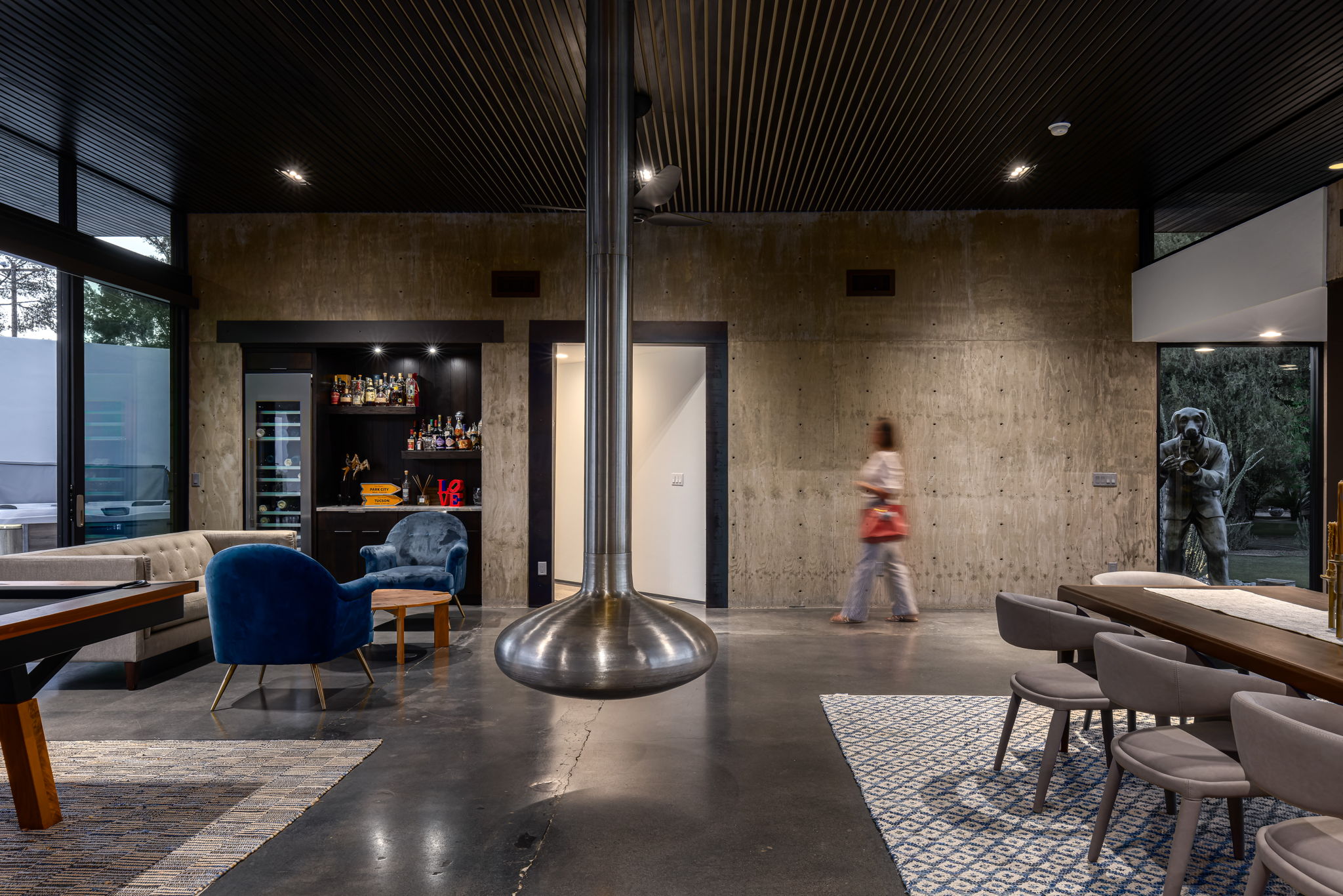 A house in Tucson's Country Club Estates at blue hour — interior with a figure in motion blur crossing the back wall, the architecture lit from within.