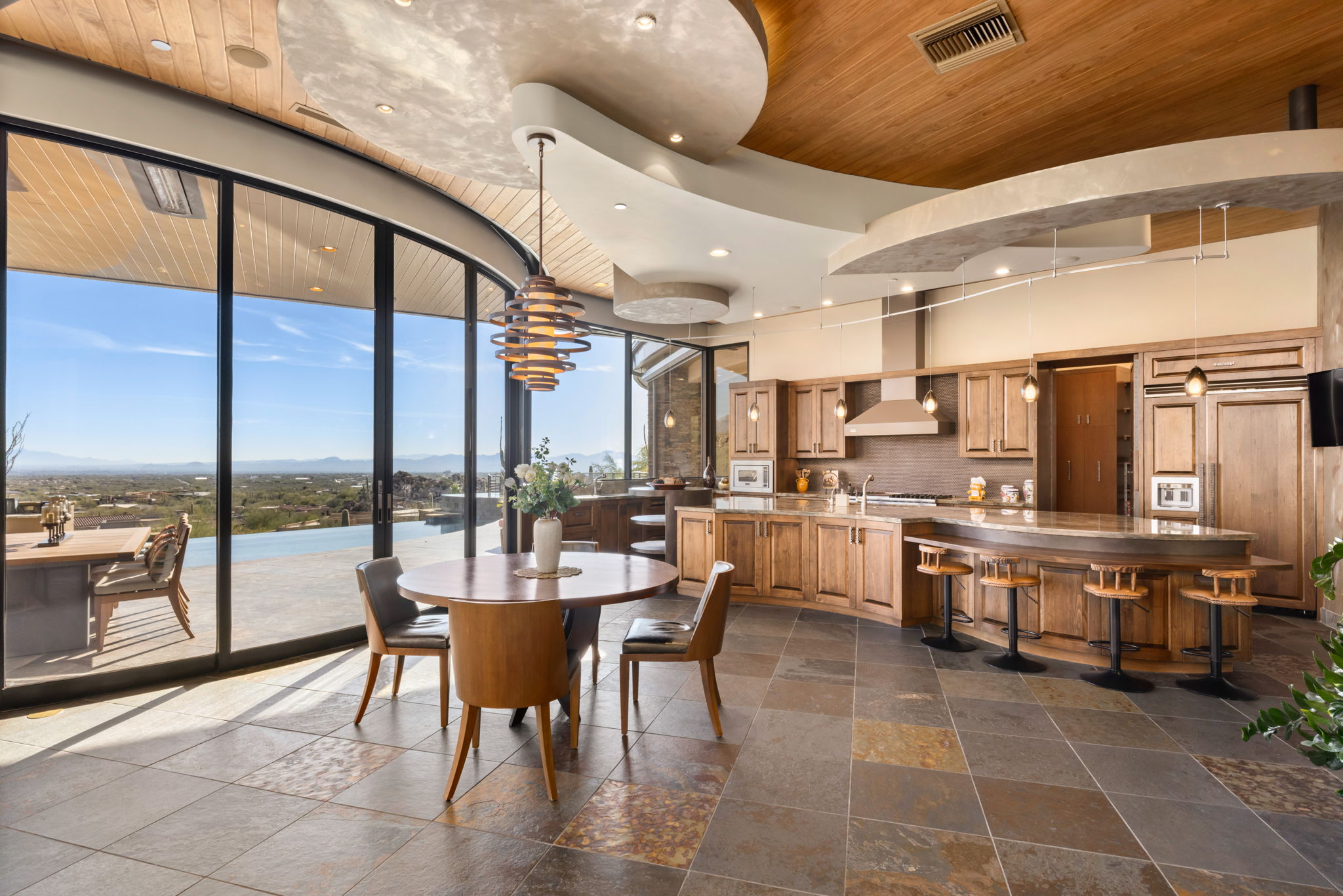 Tortolita Mountain Residence — great room with curving glass and stacked-stone fireplace